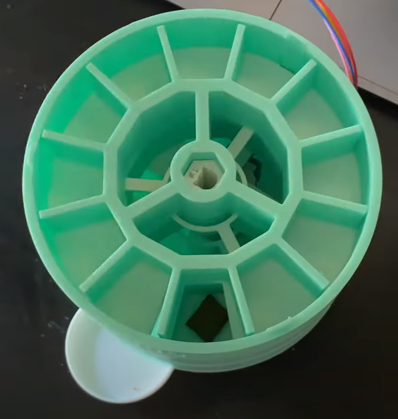 The inside of a 3d printed cat treat dispenser, showing the different compartments, shaft and wires running out the back.