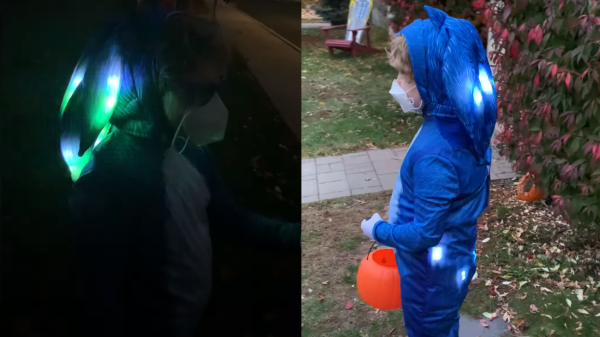 A two picture montage of a boy wearing a sonic the hedgehog costume with LEDs in them. The left picture is at night with the boy wearing sunglasses and a face mask with the sonic costume head piece lit up. The right picture is during the day with the boy wearing a face mask, holding a plastic pu mpkin bucket for candy and wearing a lit up sonic the hedgehog costume in the front yard of a house.