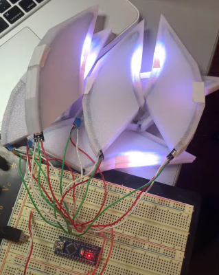 a picture of a breadboard with an Arduino Nano on it, with wires going out to 3d printed tear dropped shapes that have LED strips in them, with some LED strips on.