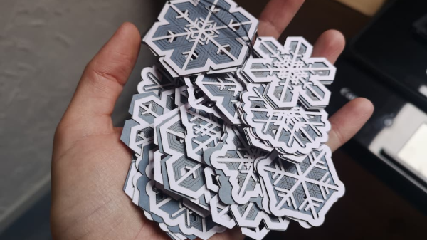 A persons handing holding a pile of generative, laser cut snowflake ornaments