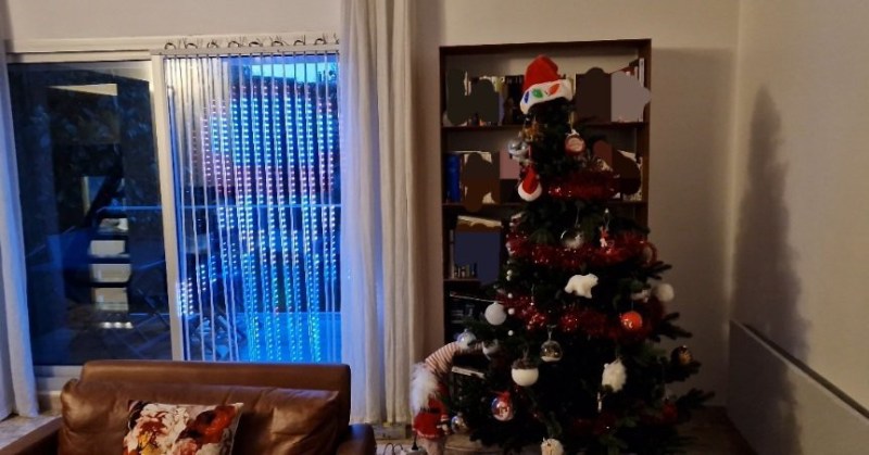 Illuminated smart curtain in front of a window, beside a Christmas tree