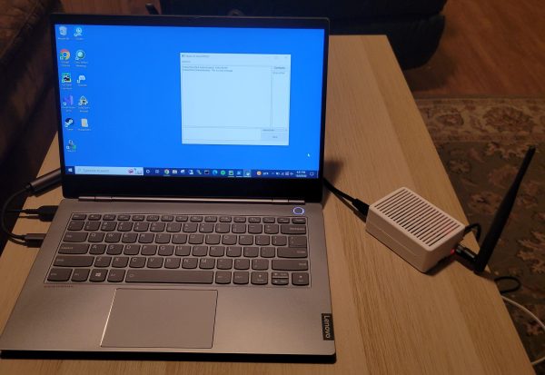 Laptop connected via Ethernet to Raspberry Pi-based secure radio device with antenna