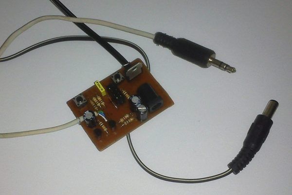 A small brown PCB with various components on it. There is a headphone cable and DC barrel connector cable coming out of it.