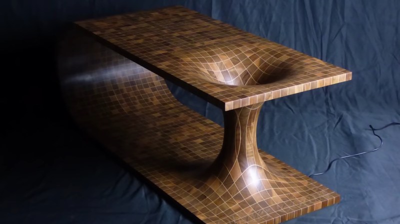 A wooden table with walnut squares and a maple grid. The table has a large barrel-shaped curve on one end and the other is a representation of a wormhole with what look like two stretched cones connected through a narrow cylinder. The wooden grid looks stretch to follow the curvature of spacetime.