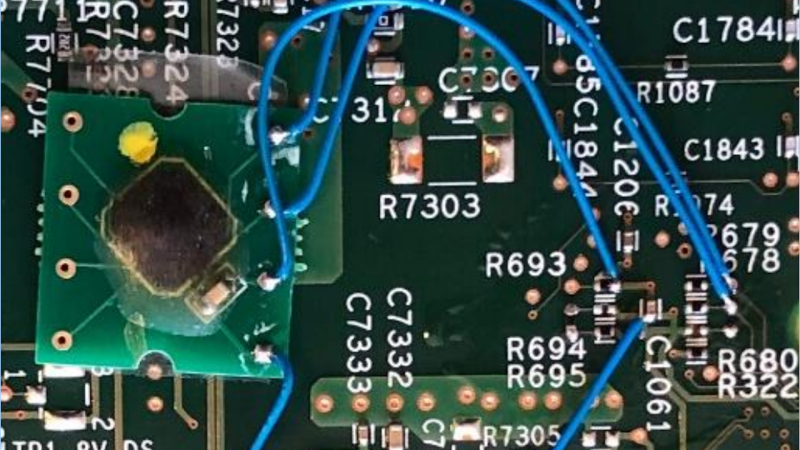A modchip described in the article - a small PCB with an epoxy blob on it, soldered to the Cisco switch PCB using four thin wires