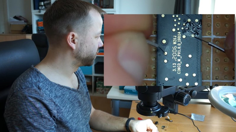 The hack's author performing the operation described at his workdesk, with a separate camera window showing the acupuncture needles being used to touch the board points