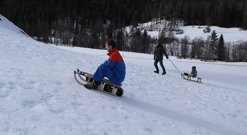 A man riding a motorized wooden sled up a snowy hill