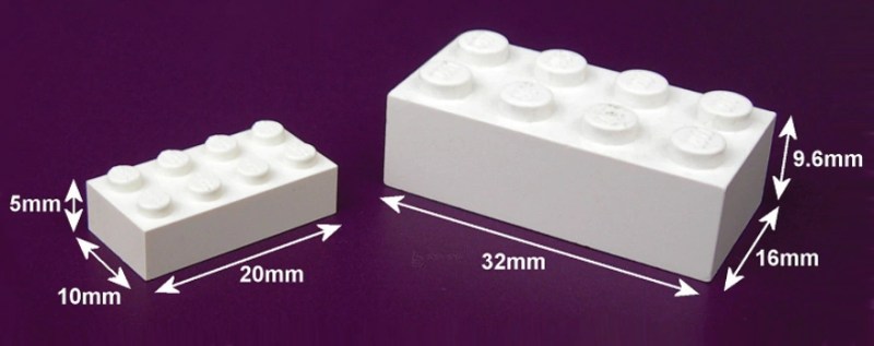 An image of a Modulex brick (left) next to a LEGO brick right. Both are 4x2 studs, but the Modulex brick is much smaller at 20x10x5 mm vs the LEGO's 32x16x9.6 mm.