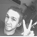 A monochrome low-resolution selfie of a man making the peace sign