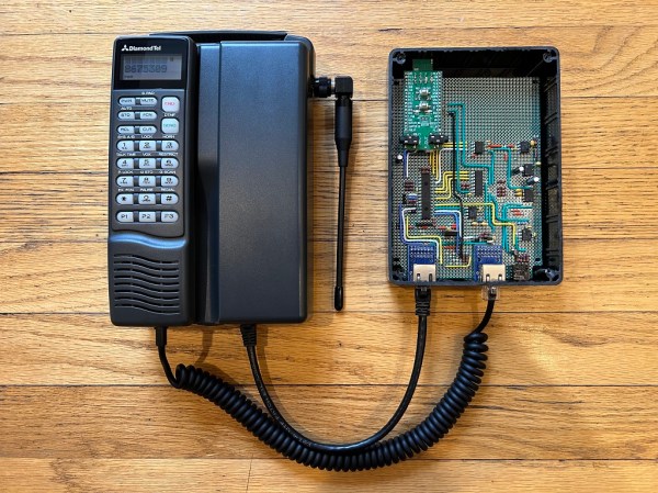 A first-generation car phone connected to a piece of prototype board with a BlueTooth module
