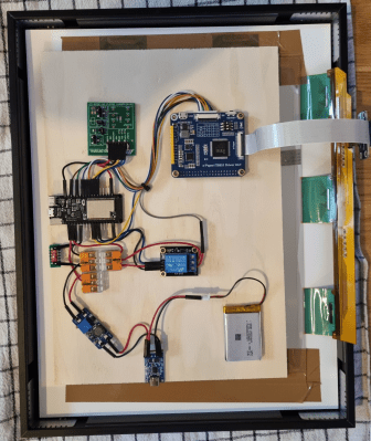 The back of a picture frame with the electronics for an e-ink newspaper display.