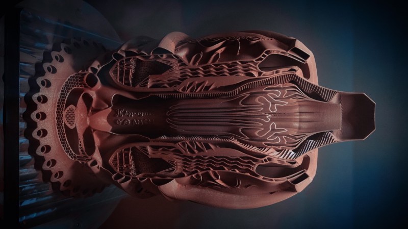 A 3D printed copper aerospike engine cutaway showing the intricate, organic-looking channels inside. It is vaguely reminiscent of a human torso and lungs.