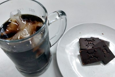 A glass of cola with Wrencher ice in it, and a plate with Wrencher chocolates.