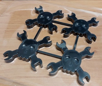 Four Hackaday Wrenchers, skull and crossed wrenches logos, encased in a vacuum formed mould.