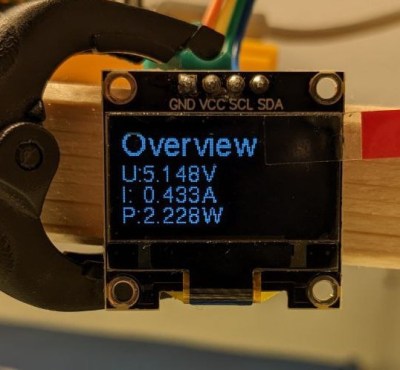 A small OLED display showing voltage, current and power measurements