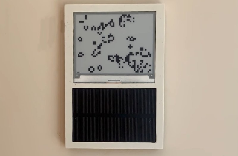 An E-ink display showing Conway's Game of Life, with a solar cell beneath it