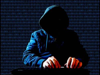 Cliche hacker in hoodie in darkened room, binary code flashing by in background.