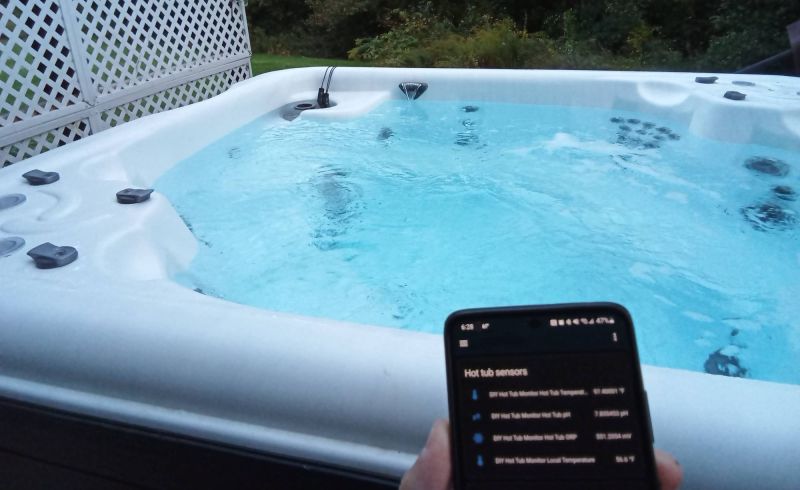 A hot tub with a smartphone in front showing real-time sensor data
