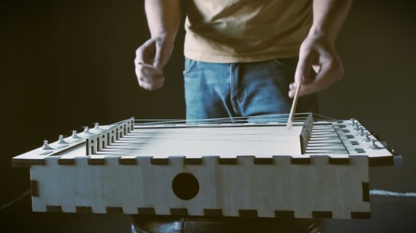 Man playing custom zither made with a laser cutter.