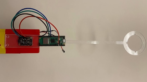 A red circuit board with four wires running from an IMU to a Pi Pico W. This is all attached to a clear plastic baton.