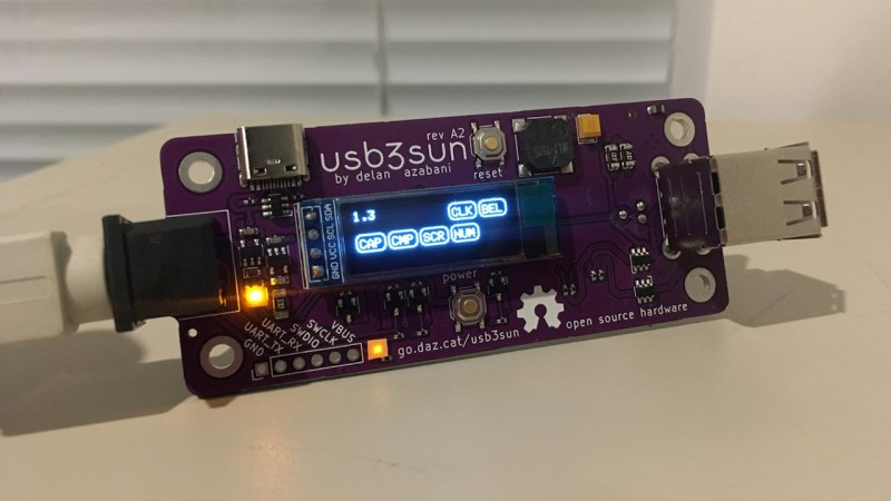 A USB3SUN adapter, connected to a SPARCstation with a cable, with the OLED screen showing status icons