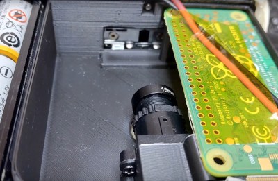 A close-up of a 3d printed Super 8 cartridge in a camera, with a Raspberry Pi Zero 2 and a little M12 camera in it.