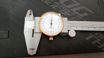 head of a dial caliper. A steel clamp like measuring tool with a watch dial. Read millimeters off the stem and hundredths off the dial