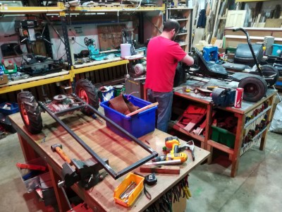 A workshop with benches that have small vehickes in various stages of construction on them.