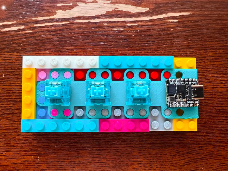 Most of a three-key macro pad featuring a 3D-printed, LEGO-compatible plate.