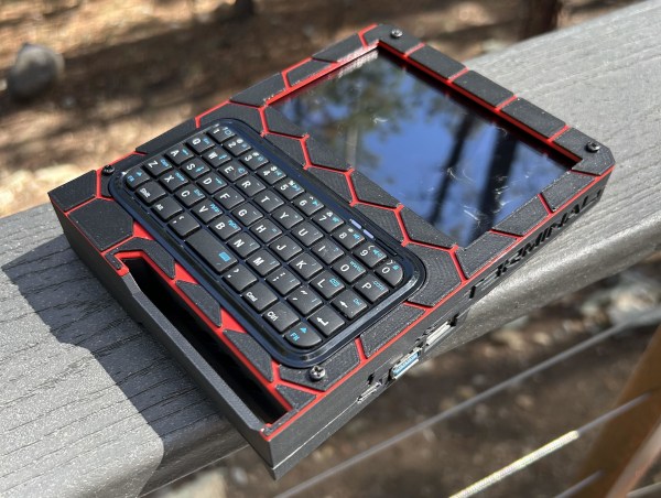 A cyberdeck/portable PC sits on a deck rail in the sun.