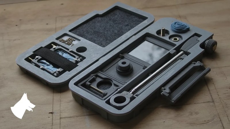 An image of a grey plastic carrying case, approximately the size of an A5 notebook. Inside are darker grey felt lined cubbies with a mirror, piece of glass, a viewfinder, and various small printed parts to assemble a camera lucida.