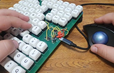 A pair of hands using a one-handed keyboard and a trackball mouse. 