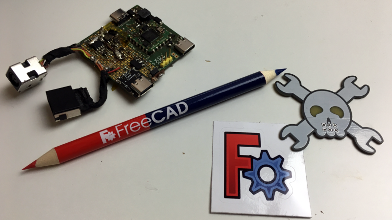 A FreeCAD sticker, a FreeCAD pencil, a Hackaday Jolly Wrencher SAO PCB and the board-to-be-encased next to each other