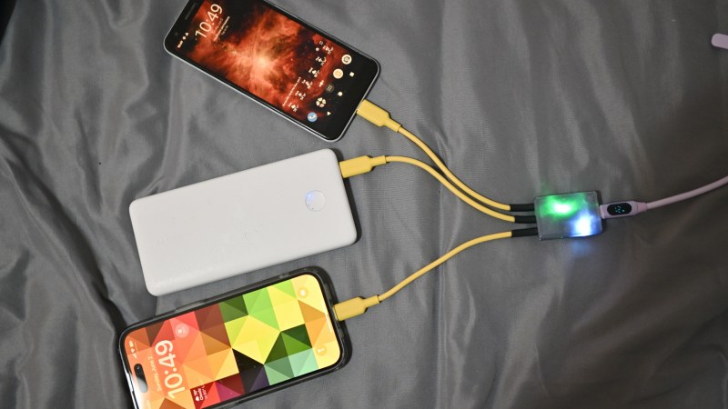 The splitter with a 3D-printed case and three yellow cables coming out of it, powering two phones and one powerbank at the same time