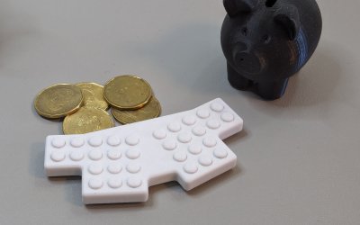 A very small keyboard with some coins and a 3D-printed piggy bank for size comparison.
