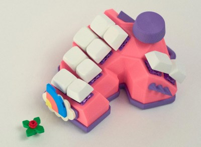 A pink and purple 10-key keyboard with a rotary encoder, spikes, and a custom area with LEGO attached.