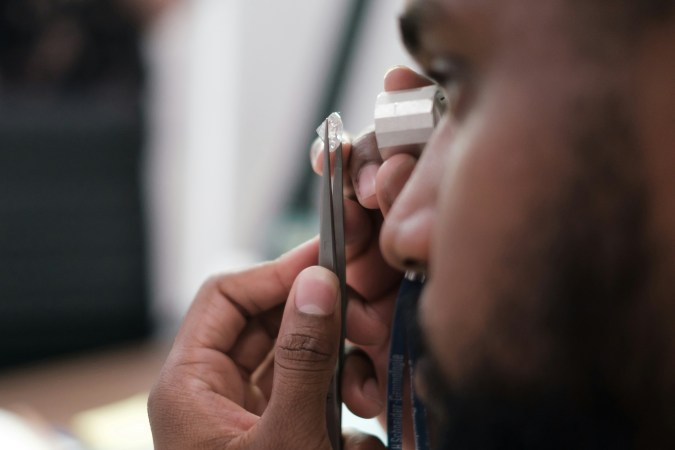 A person examines a diamond with a loupe.