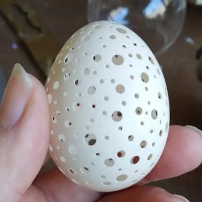 A standard chicken's egg with many holes both large and small.