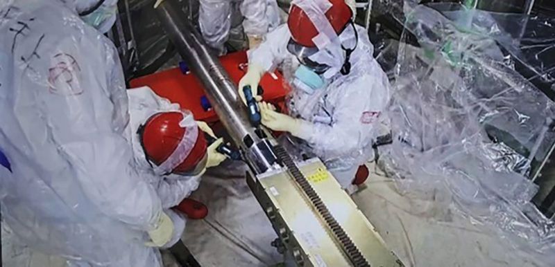 TEPCO employees connect pipes that push the 'Telesco' robot into the containment of Unit 2 for core sample retrieval. (Credit: TEPCO)