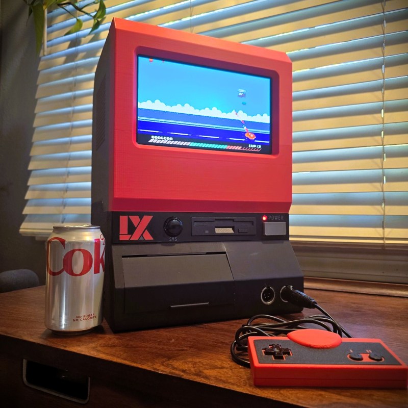 A replica LX System game console inspired by the UFO 50 video game sitting on a wooden desk next to a can of diet Coke.