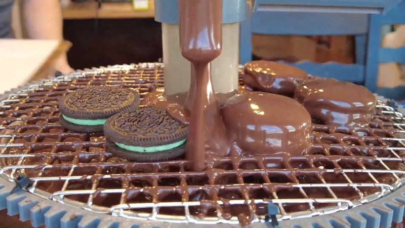 A chocolate coating machine works in the round to enrobe mint Oreos.