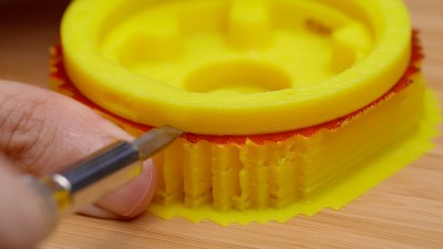 A photo of a 3D printed yellow plastic form with red marker drawn on the top of the support material and used in Engineer Bo's Precision Bluetooth Scroll Wheel