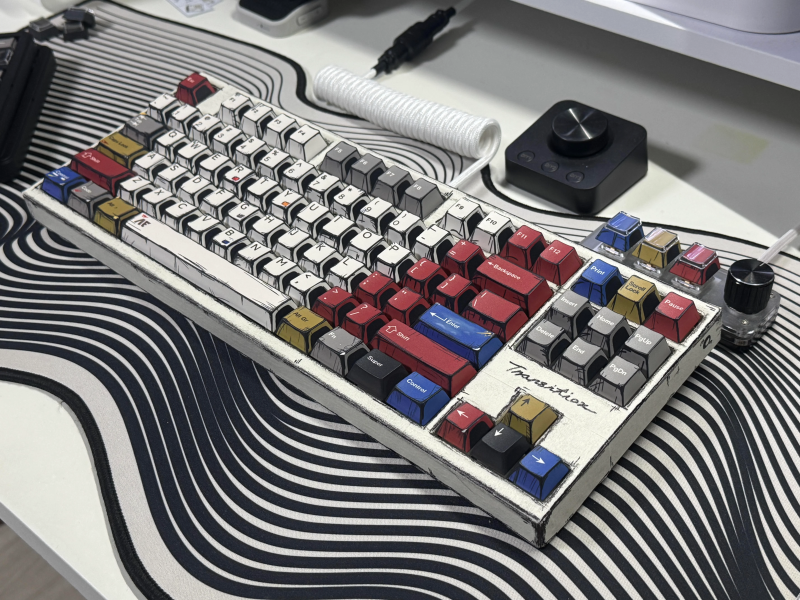 A comic book-inspired keyboard on a wavy black and white desk mat.