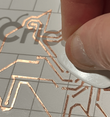 Smoothing down the copper traces with a guitar pick.