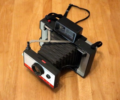 A Polaroid folding bellows camera on a wooden table.