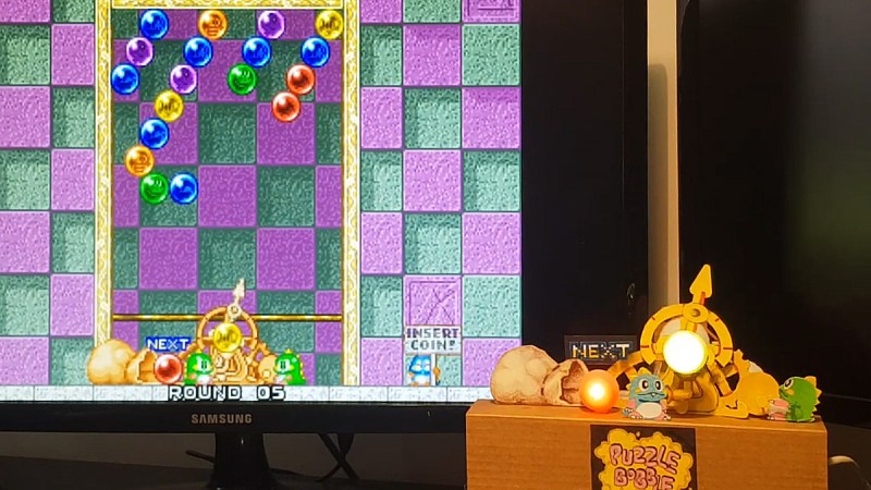 Puzzle Bobble on a screen with a physical gadget in front