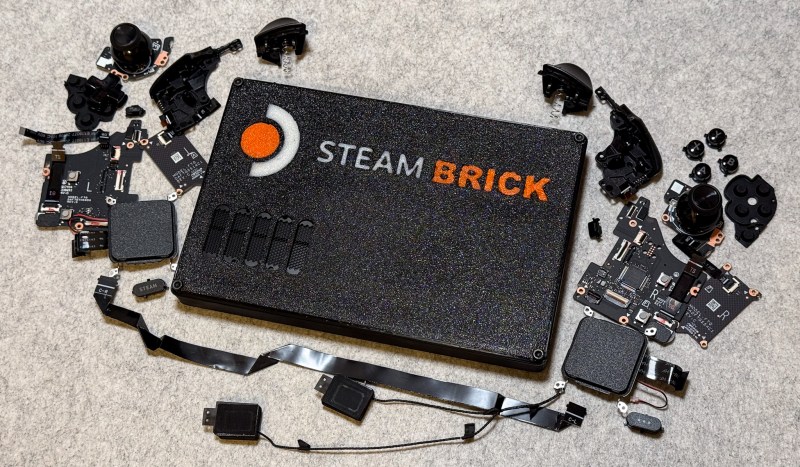 A black box with the words "Steam BRICK" emblazoned in white and orange text. It sits on a grey surface with various electronic parts surrounding it.