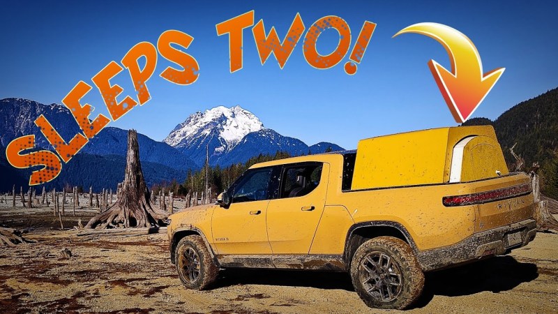 A bright yellow crew cab pickup is on an unpaved area with snow-capped mountains in the distance. In its bed is a matching camper shell which is somewhat trapezoidal with a smaller semicircular section that can pull out to lengthen the sleeping space of the camper. At the top of the image it says, "Sleeps Two!" with an arrow pointing to the camper shell.