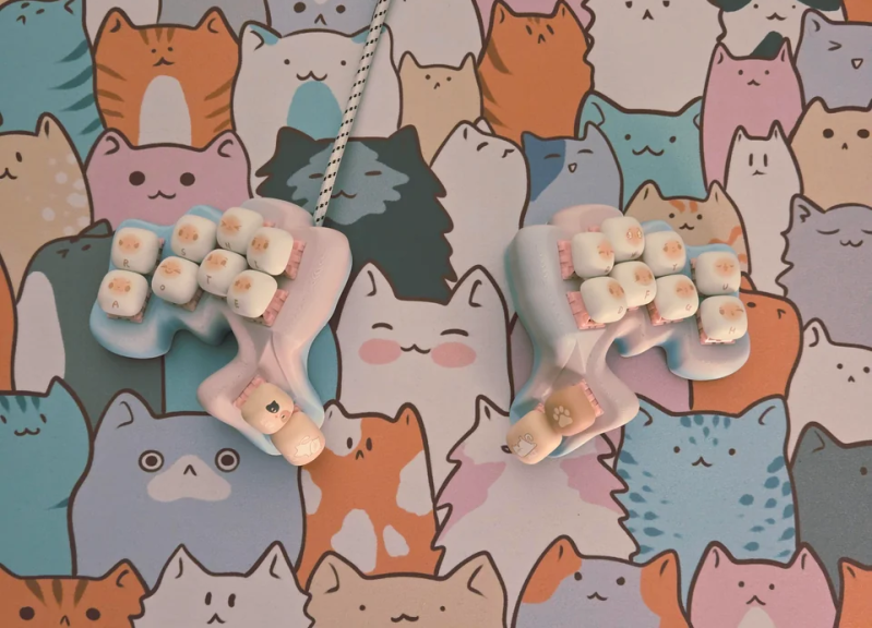 A cat-keycapped keyboard napping on a multi-cat desk mat.