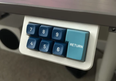 A desk-mounted macropad in two shades of blue, featuring ISO Return.